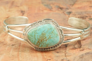 Genuine Number 8 Mine Turquoise Stones set in heavy gauge Sterling Silver Bracelet. Created by Navajo Artist John Nelson. Signed by the artist. The Number 8 mine is located in Eureka County Nevada. Since 1976 there has been no Number 8 Turquoise mined. There is however, an existing stock pile that Mr. Dowell Ward, the last owner of the Number 8 mine, had stocked away for later sorting. The Turquoise is a collector's item--because once the reserve is gone there will be no more material released onto the market. The Gold Mining Company owns the claim to the Number 8 mine and it has been swallowed up by the gold mining operations. This is some of the last Number 8 Turquoise to be had and will be a great addition to your collection. 
